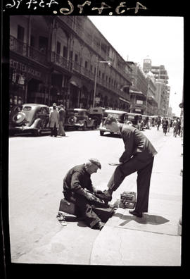 Johannesburg, 1935. Shining shoes on pavement.
