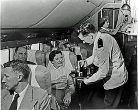 
SAA Douglas DC-7B interior, cabin steward serving drinks. Hostess. Note girl in sleeper bunk.

