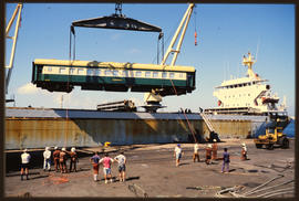 Passenger coach of Hotham Valley Railway lifted by harbour crane from ship in harbour.