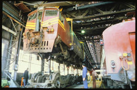 Locomotive lifted off bogies in railway workshop.