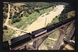Aerial view of coal train on high concrete arch bridge. Banner with '100 000 000 ton Export Coal'...