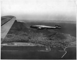 Cape Town. Trans World Airlines, TWA, Lockheed Constellation in flight over Table Bay Harbour sho...