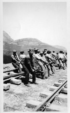Team of workers lifting railway track with crowbars. (Lund collection)