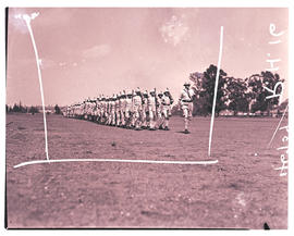 
Army recruits in training, marching on parade ground.
