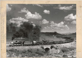 A Belpaire boiler SAR Class 6 heads a SAR Class 24 on a goods train going over stone culvert.