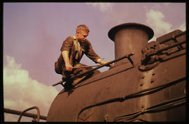 Fitter fixing cowl to steam locomotive.