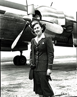 
SAA Lockheed Constellation hostess Miss Manchip standing next to engine.
