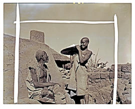 Northern Transvaal, 1946. Bavenda girl presenting basket to old man.