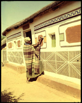 Pretoria district. Ndebele woman decorating traditional home.