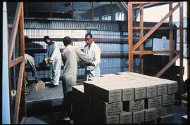 
Workers loading boxes of furniture polish into container.
