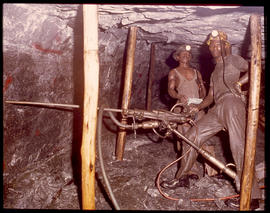 Miners underground with rock drills.