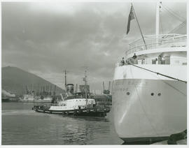 Cape Town, 1961. Harbour tug 'FT Bates' guiding 'Pendennis Castle' into Table Bay Harbour.